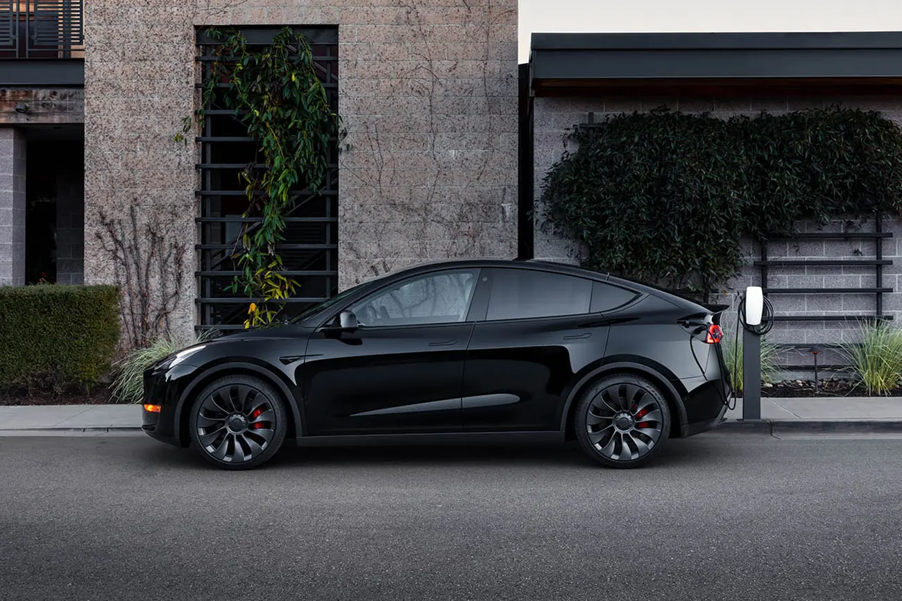 Tesla Model Y noire vue de profil, garée devant une façade